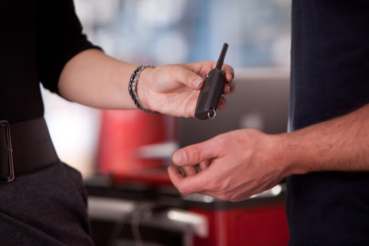 Woman handing car key to another