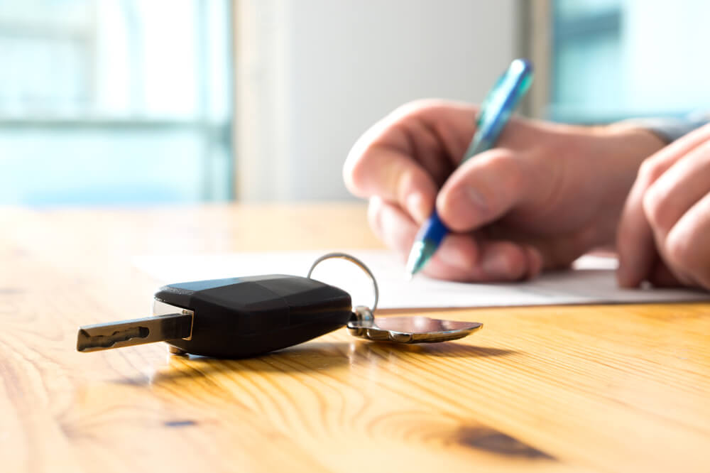 A man signs vehicle transport documents for his car. Reviewing the documents to make sure he avoids any auto transport scam.