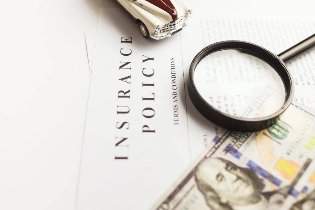Insurance Policy with a magnifying glass and a dollar bill. Car shipping from Hawaii