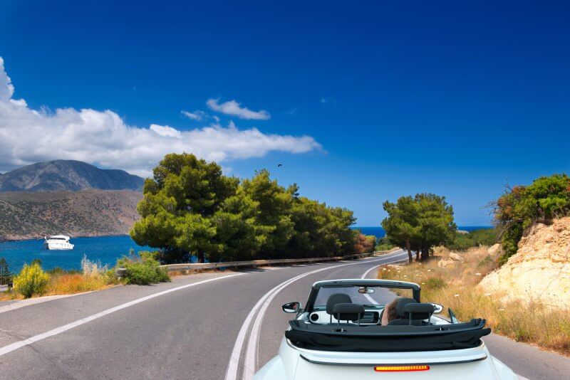 Convertible on an open road next to the sea.