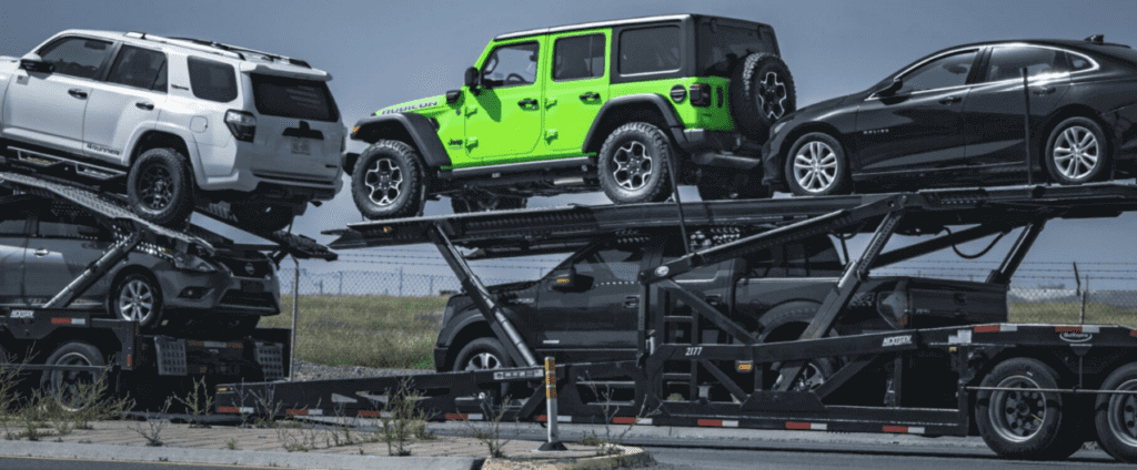 An open auto transport trailer with 5 vehicles loaded. If you want to ship a car and enclosed transport, we can provide this service.